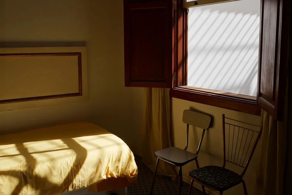 Quiet bedroom with sunlight coming through open wooden window shutters